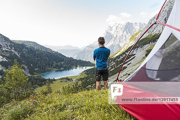 Austria  Tyrol  Hiker standing at his tent in the mountains  looking at Lake Seebensee