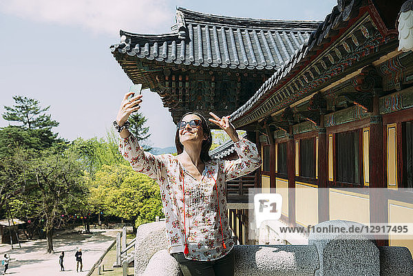 South Korea  Gyeongju  happy woman taking a selfie with cell phone in Bulguksa Temple