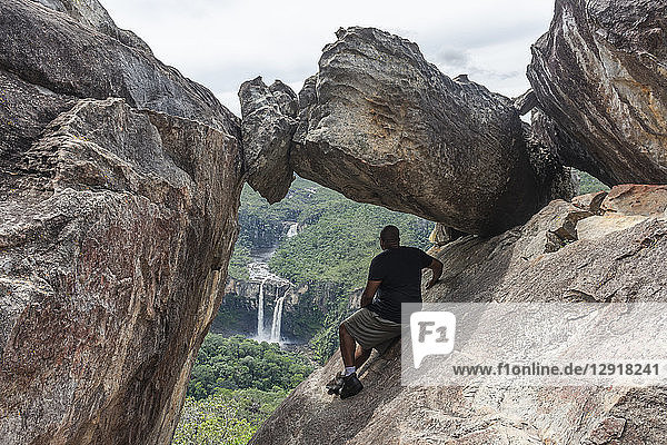Rückansicht eines Wanderers  der auf einer Felsformation sitzt  Mirante da Janela  Chapada dos Veadeiros  Goias  Brasilien