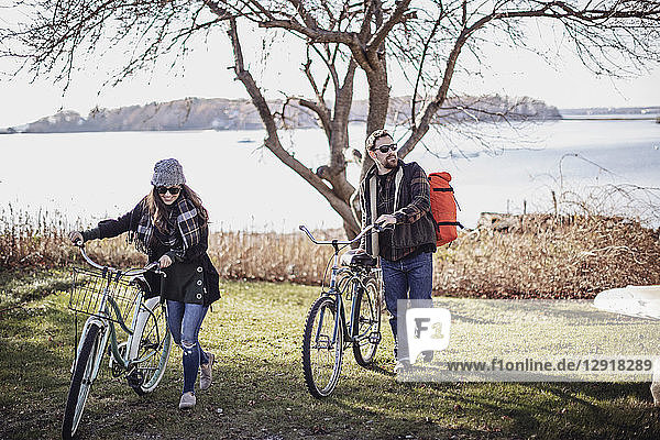 Paar  das mit dem Fahrrad über eine Wiese fährt  mit dem Meer im Hintergrund  Peaks Island  Maine  USA