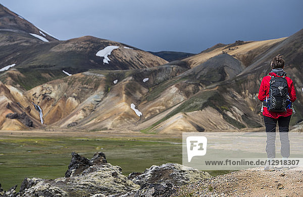 Wanderer bewundert die Landschaft mit Rhyolithbergen bei Landmannalaugar auf dem Laugarvegur-Wanderweg bei Tageslicht  Landmannalaugar  Fjallabak  Island