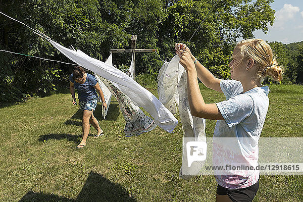 Eine Frau und ein Mädchen im Teenageralter hängen Wäsche zum Trocknen auf eine Wäscheleine im Freien
