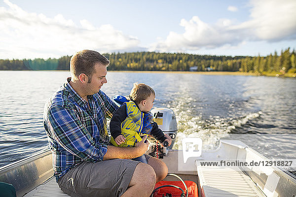 View of father and son spending time together on motorboat in lake  Kamloops  British Columbia  Canada
