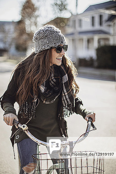 Junge Frau lacht beim Fahrradfahren durch ein Dorf im Herbst  Peaks Island  Maine  USA