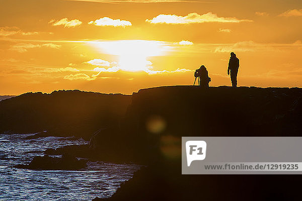 Silhouetted view of two photographers capturing setting sun on Reykjanes Southern Peninsula  Reykjanes  Iceland