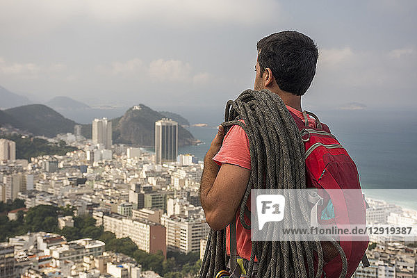 Male adult climber on rocky edge with a view to mountains and the city  Agulinha de Copacabana in Rio de Janeiro  Brazil