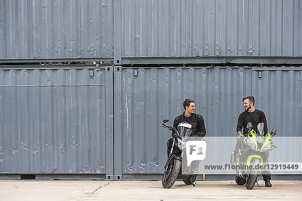 Zwei Freunde sitzen nebeneinander auf Motorrädern und unterhalten sich  Bangkok  Thailand