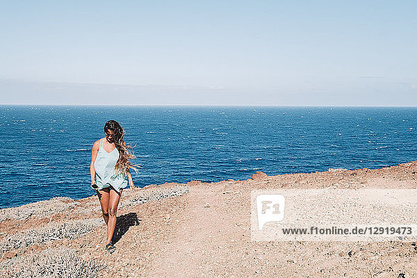 Frau  die tagsüber an einem flachen Küstenabschnitt mit dem Meer im Hintergrund spazieren geht  Teneriffa  Kanarische Inseln  Spanien