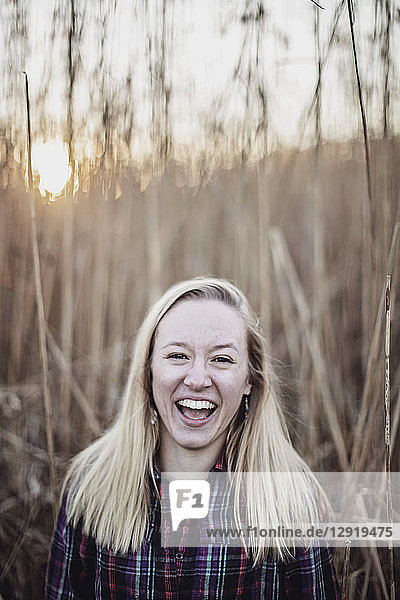 Lachende junge Frau  die vor langem Gras im Herbst steht  Peaks Island  Maine  USA