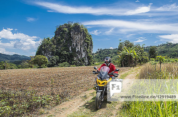 Vorderansicht eines Mannes auf einem Motorrad auf einer unbefestigten Straße  Chiang Rai  Bezirk Mueang Chiang Rai  Thailand