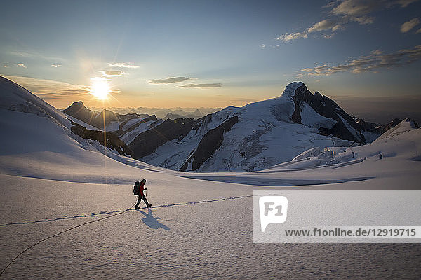 Seitenansicht eines Mannes  der bei Sonnenuntergang während der Besteigung des Mount Robson durch den Schnee wandert  British Columbia  Kanada