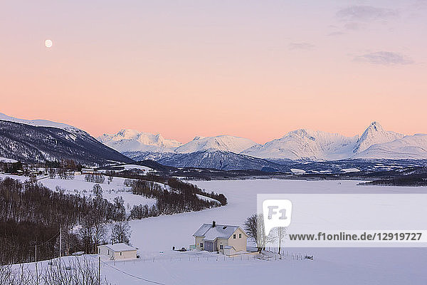 Sonnenaufgang über einem typischen Haus mit den Lyngen-Alpen im Hintergrund  Mestervik  Provinz Troms  Norwegen  Skandinavien
