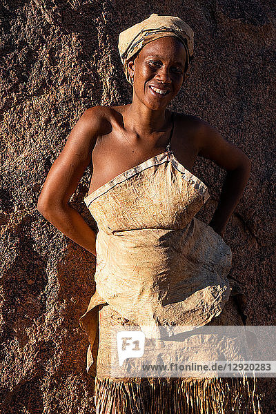 Porträt einer Frau  die sich in einem Damara-Stammesdorf in der Nähe von Twyfelfontein  Namibia  in der Sonne auf einem Felsen ausruht
