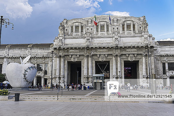 Milan Railway station facade with artwork of The Reintegraded Apple sculpture outside Milano Centrale at Piazza Duca dAosta  Milan  Lombardy  Italy