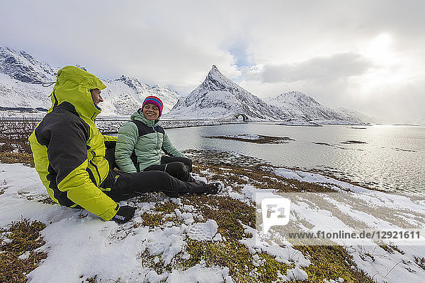 Wanderer auf schneebedeckten Wiesen mit Volanstinden im Hintergrund  Fredvang  Lofoten  Nordland  Norwegen