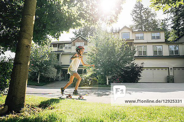 Tween Girl Skating on Skateboard on Sidewalk in Residential Neighborhood