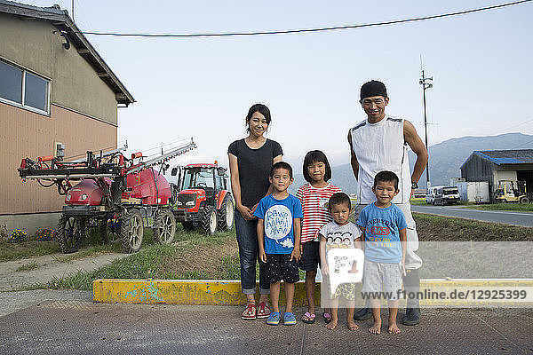 Portrait of Japanese farmer  his wife and four children standing in their yard.