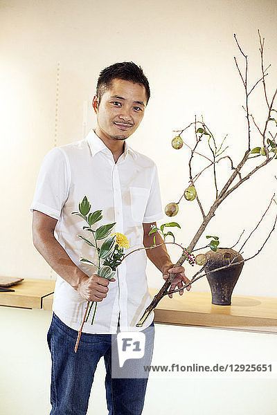 Japaner  der in einer Blumengalerie arbeitet und am Ikebana-Arrangement arbeitet.