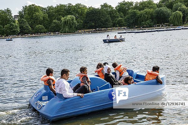 United Kingdom Great Britain England  London  Royal Parks  Hyde Park  green space  The Serpentine  recreational lake  pedal paddle boat  Asian  man  woman  girl  boy  child  family  mother  father  son  daughter  Muslim  headcover  life jacket vest  flotation device  safety