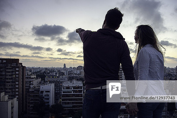 Paar steht auf einer Terrasse und schaut auf die Stadtlandschaft