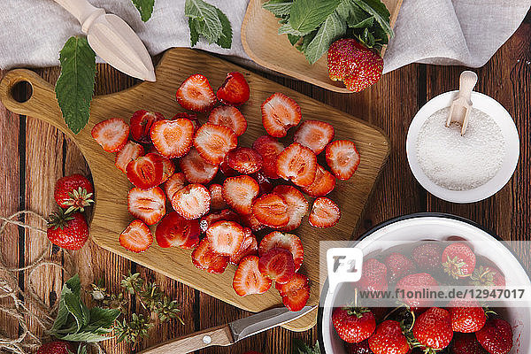 Frische Erdbeeren  geputzt und in Scheiben geschnitten  und eine Schale mit Zucker
