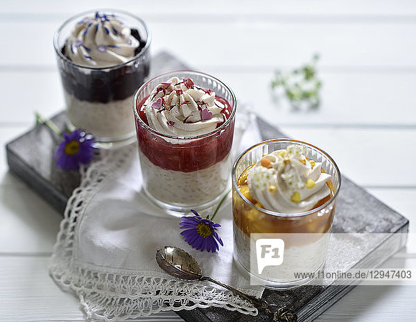 Vegane Milchreis-Desserts im Glas mit Aprikose-Mango-  Himbeer-Rhabarber- und Blaubeer-Sauce  dekoriert mit Kokossahne und BlÃ¼ten