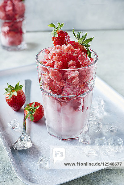Erdbeergranita in einem Cocktailglas mit frischen Erdbeeren und Eiswürfeln