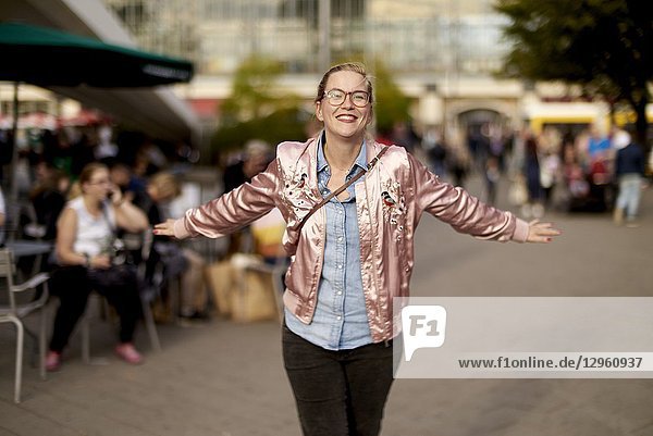 Lively woman with open arms dancing at Alexanderplatz  Berlin  Germany