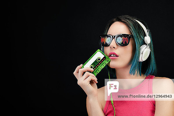 Junge Frau hält eine Audiokassette in der Hand