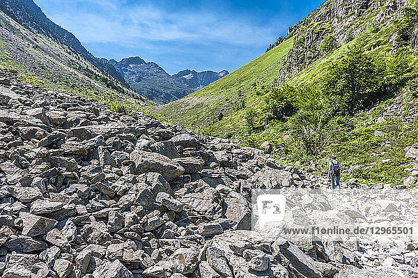 France  Pyrenees National Park  Occitanie region  Val d'Azun  Haute-vallee d'Estaing  hiker on a track by a mass of fallen rocks