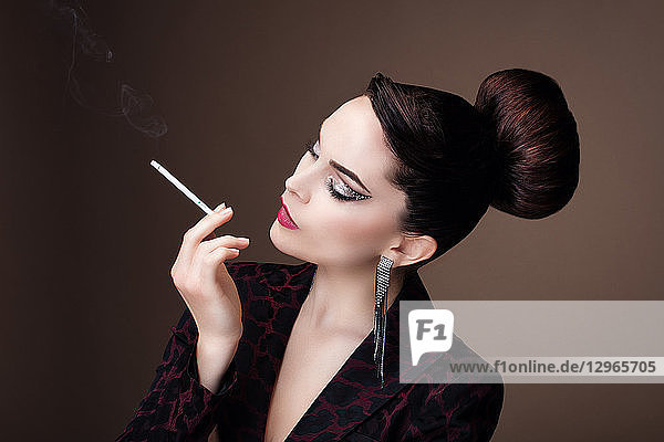 Porträt einer jungen Frau im Profil  die eine feine Zigarette raucht