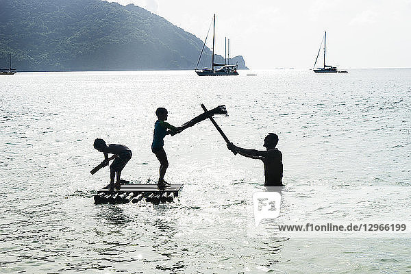 Ein Vater und seine beiden Söhne spielen auf einem Floß auf dem Meer  Charlotteville  Tobago  Trinidad und Tobago  Westindien  Südamerika