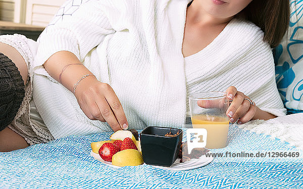 Tight shot of a young woman having breakfast in her room