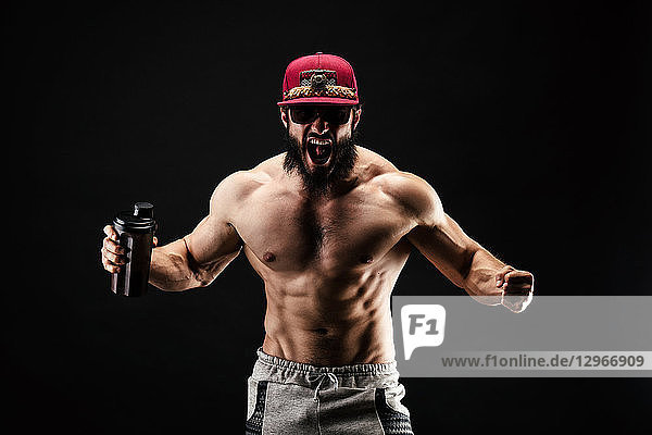 Ein schreiender Bodybuilder mit einem Proteinshaker in der Hand