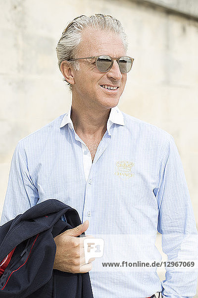 Portrait of a beautifull smiling mature man in sky blue shirt and sunglasses.