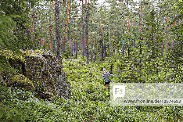 Woman walking through forest in Ostergotland Sweden
