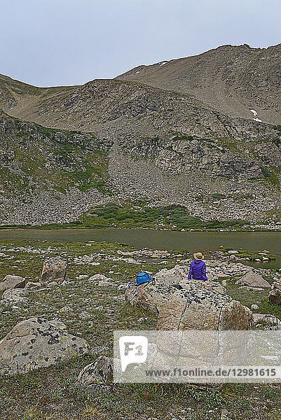 Frau ruht sich auf einem Felsen am See aus  während sie in Herman Gulch  Colorado  wandert