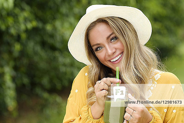 Smiling young woman with smoothie in mason jar