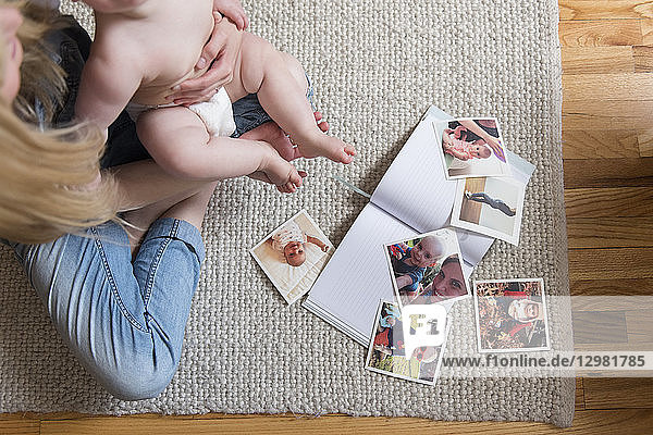 Fotografien und Buch von Mutter und Tochter auf einem Teppich sitzend