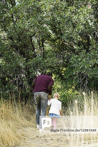 Mann geht mit seiner Tochter im Wald spazieren