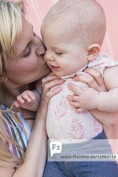 Ein kleines Mädchen wird von seiner Mutter geküsst