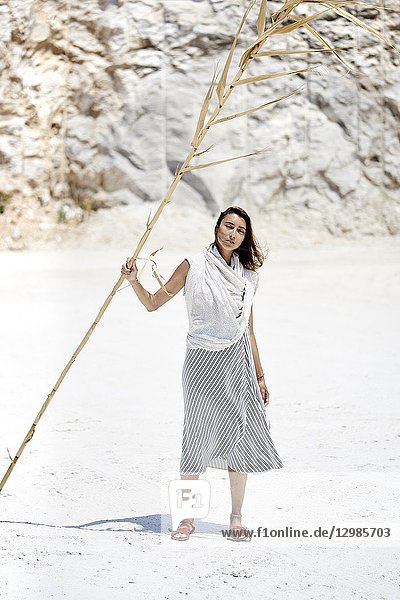 Woman with dry bamboo stick in desert