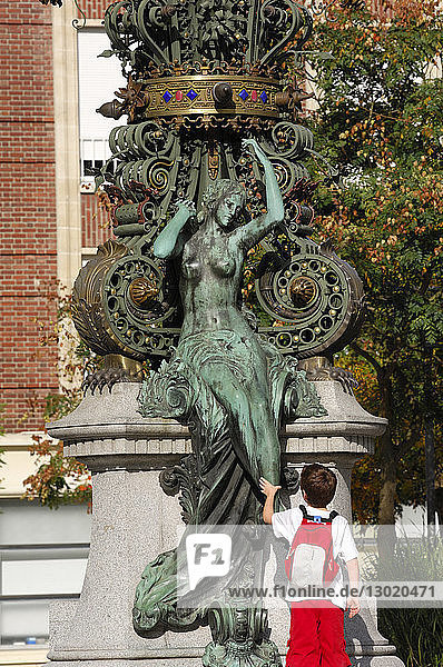 France,  Somme,  Amiens,  child in front of the famous Dewailly Clock touching the support statue,  called Marie sans chemise (Mary without a shirt) by sculptor Albert Roze