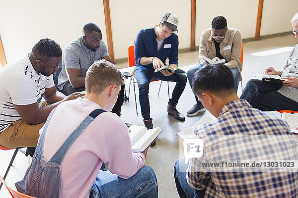 Men reading and discussing bible in prayer group