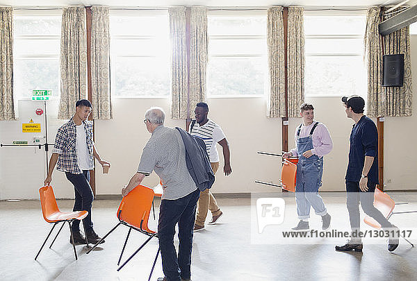Männer stellen Stühle für die Gruppentherapie im Gemeindezentrum auf