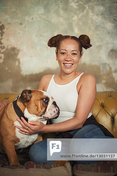 Portrait smiling young woman petting dog on sofa