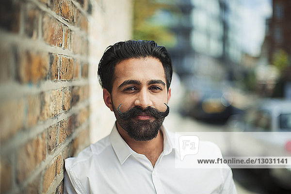 Portrait confident young man with handlebar mustache on urban sidewalk