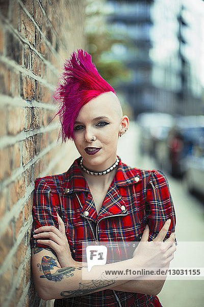 Portrait confident young woman with pink mohawk on urban sidewalk