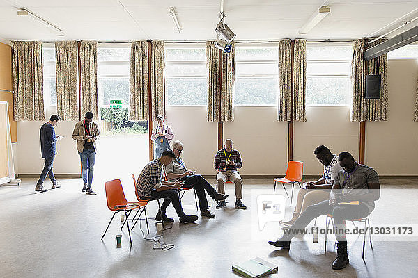 Wartende Männer,  die Smartphones im Gemeindezentrum benutzen