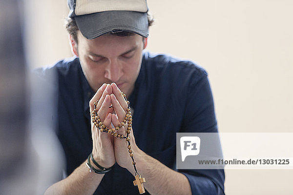 Mann betend mit Rosenkranz